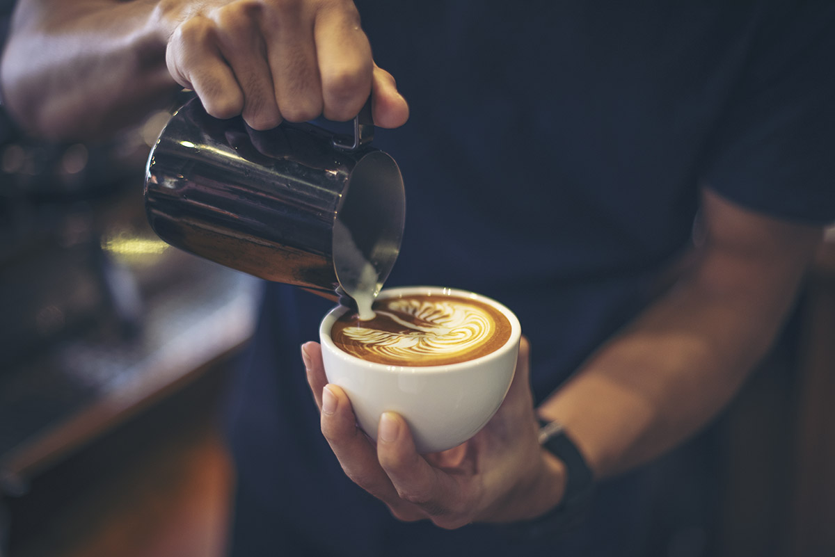 Milchschaum wird für Latte Art in einen Espresso gegossen